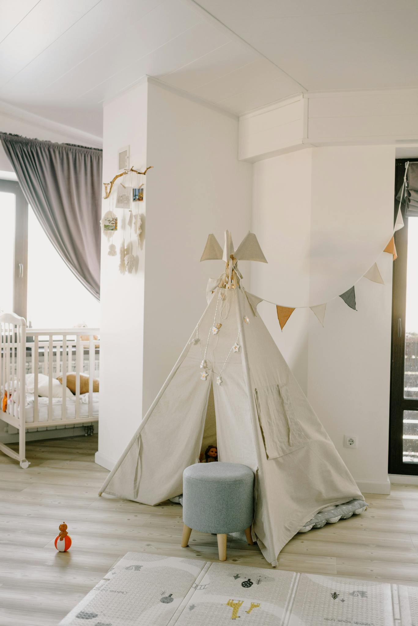 A bright, stylish kids room featuring a play tent, crib, and playful decor.