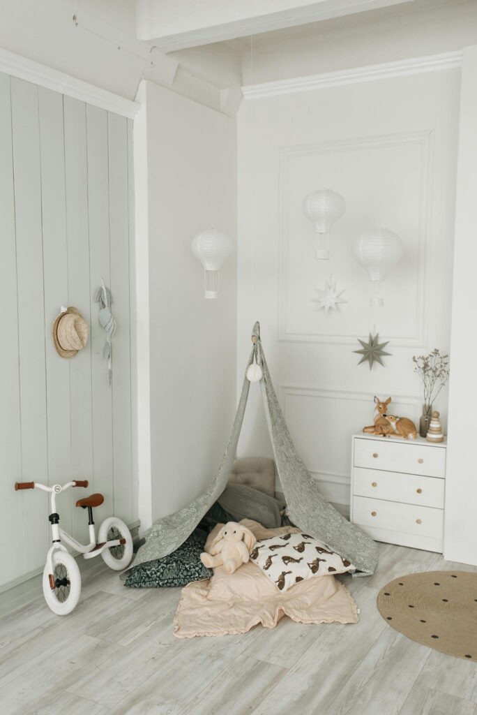 A charming children's room featuring a play tent, white bicycle, and soft decor elements.